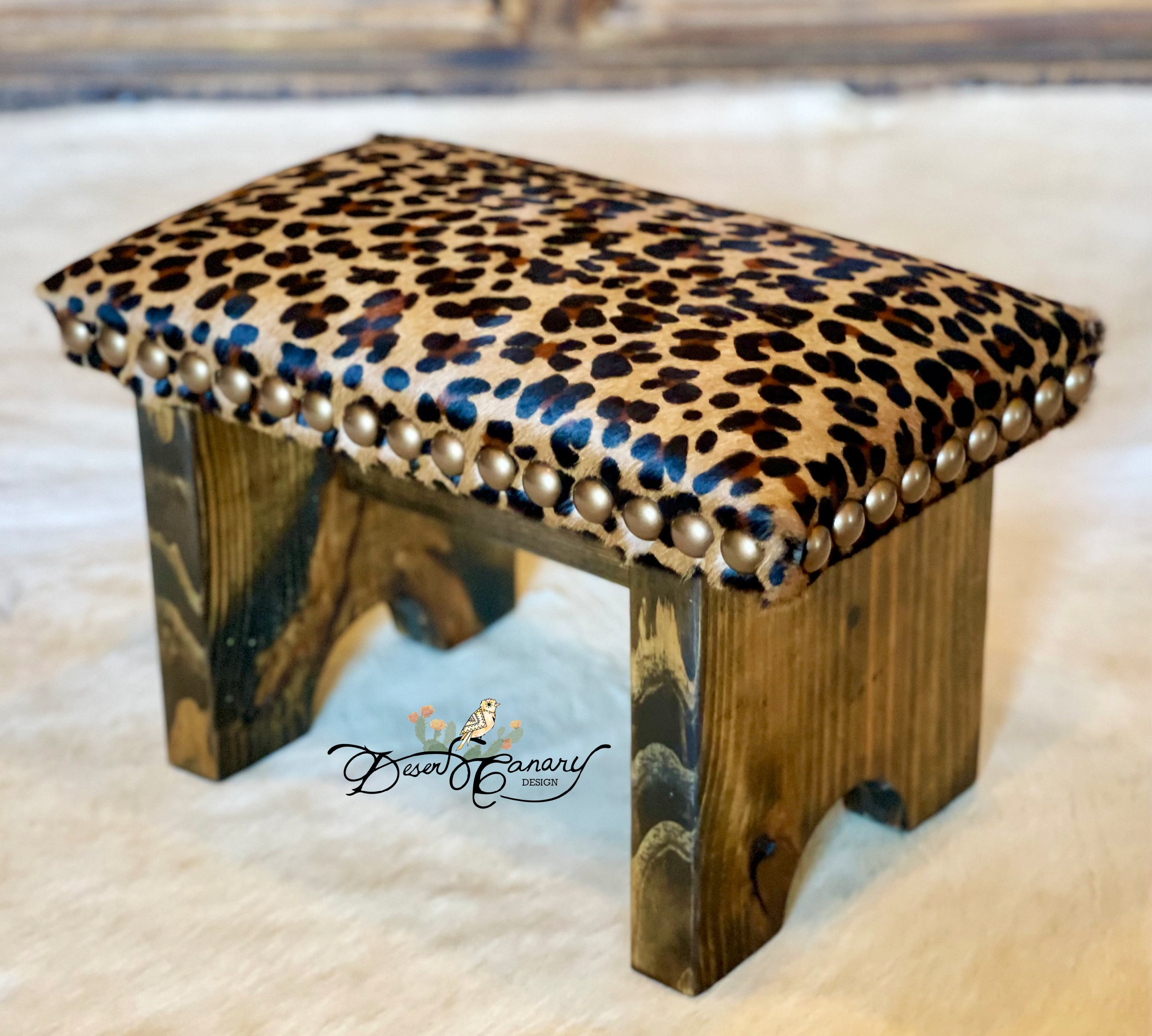 Wooden stool with leopard print cushion and pearl accents on a light background