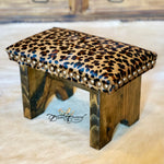 Wooden stool with leopard print cushion and pearl accents on a light background